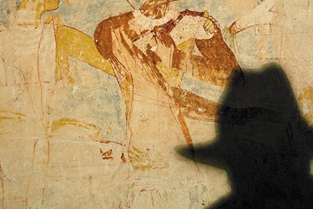 Zahi Hawass, shown in silhouette inspecting murals in Giza, laments the halt of many restoration projects since his departure. "Antiquities are collapsing in front of my eyes," he says.