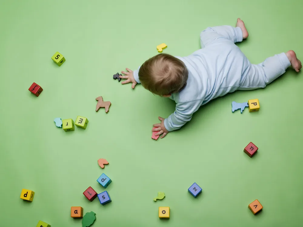 Aerial view of a baby on all fours playing with blocks