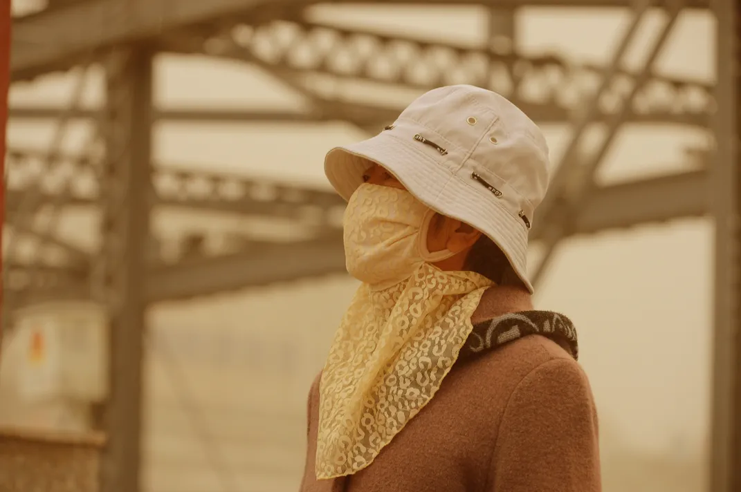 A woman wearing a face mask walks on a road in a sandstorm in Lanzhou city, northwest Chinas Gansu province, 24 April 2014 Credit: Imaginechina/Corbis