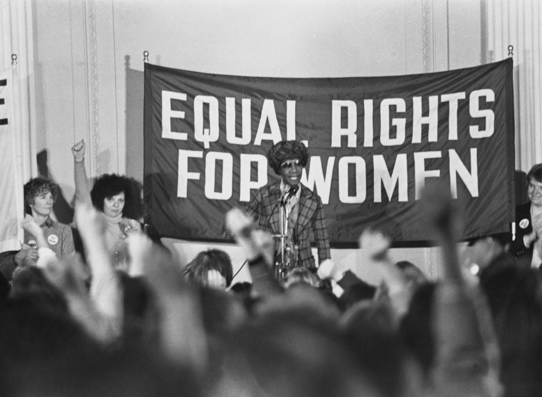 Chisholm in front of an equal rights for women banner