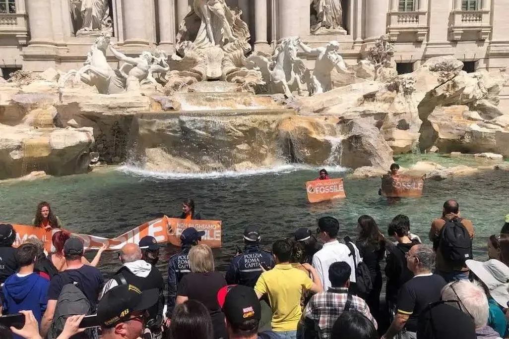 Protesters hold signs amid water with patches of black