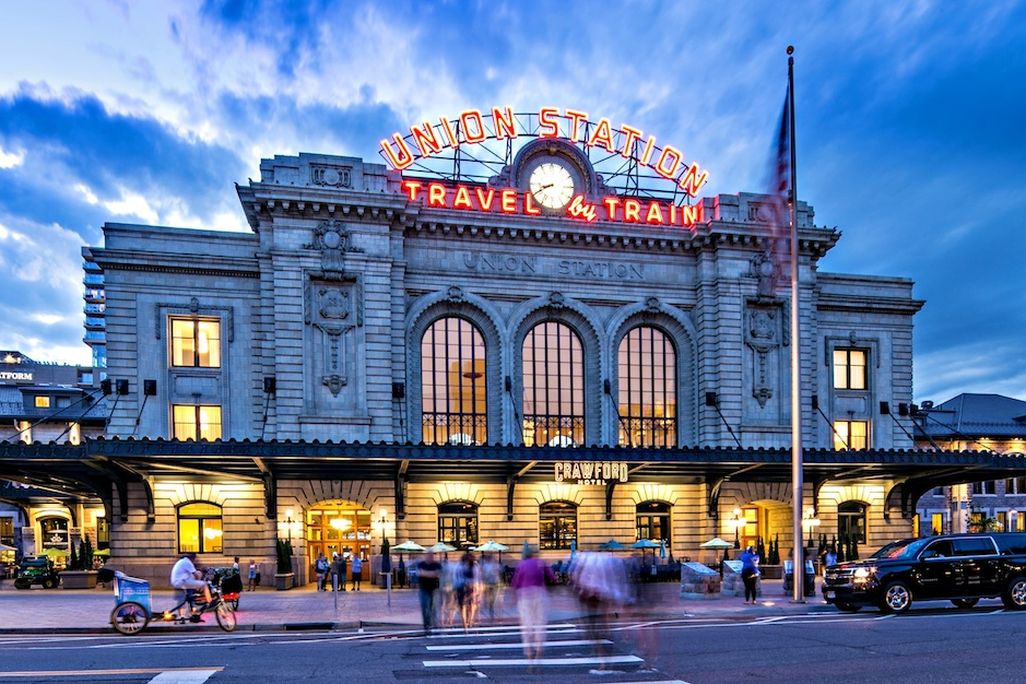 A large building at dusk with a sign that says Union Station Travel by Train