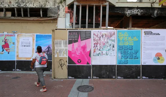 A person looking at a wall of posters in front of a building under construction