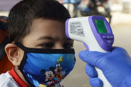 A doctor checks the temperature of a child at a mobile clinic.
