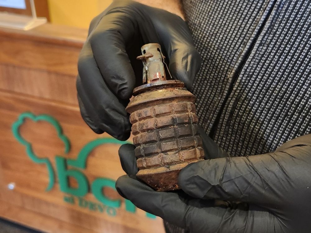 A pair of hands wearing black gloves holding a grenade