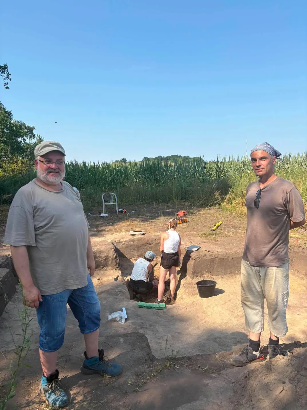 Two men stand at the site of an excavation