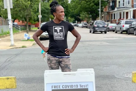 Surgeon Ala Stanford takes a pause from testing while standing near one of her group's signs in North Philadelphia.
