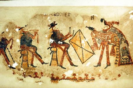 This wall painting features musicians in European clothing on the left and a dancer in a traditional feathered cape on the right.  