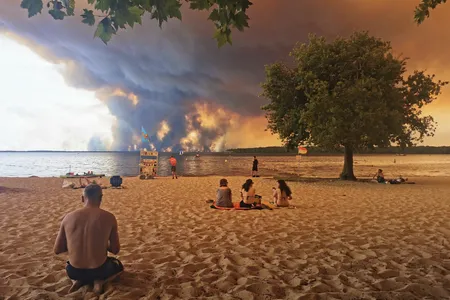 Beachgoers rested at Lake Lacanau's&nbsp;Moutchic&nbsp;Beach in southwestern France last week, as clouds of smoke rose into the sky from the Gironde wildfire.