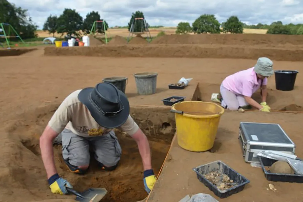 Archaeologists digging in sediment searching for artifacts at a dig in Rendlesham