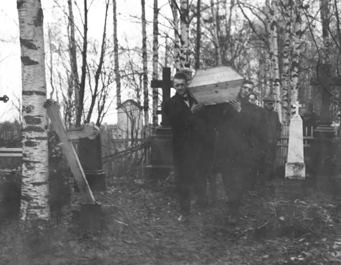 Men carry a casket among birch trees and tall cross headstones
