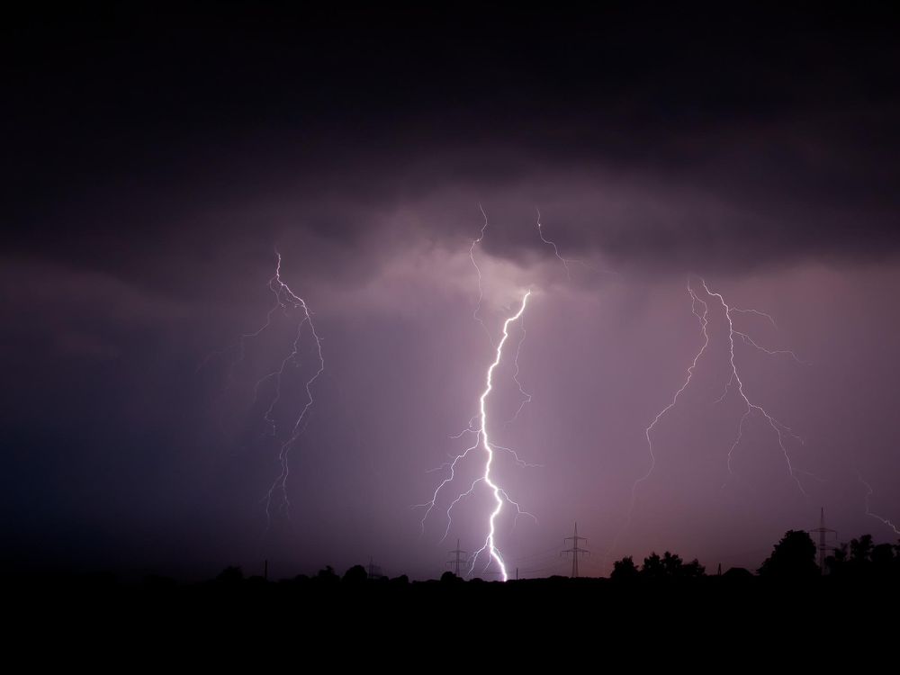 A photo of lightning striking the ground against a moody purple sky