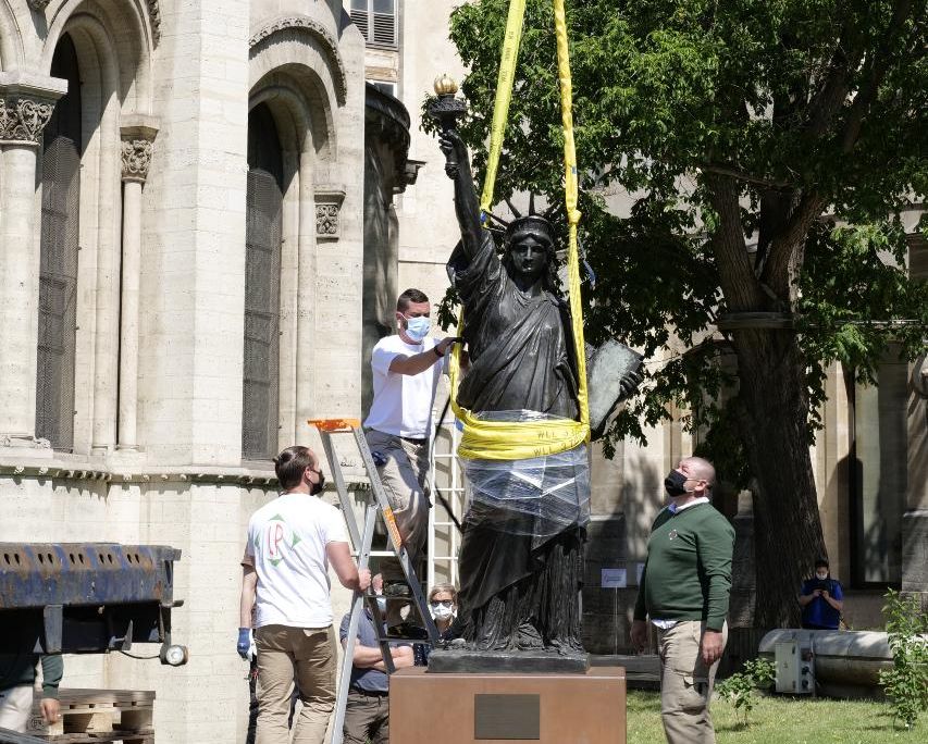 Workers remove a Statue of Liberty replica from its plinth