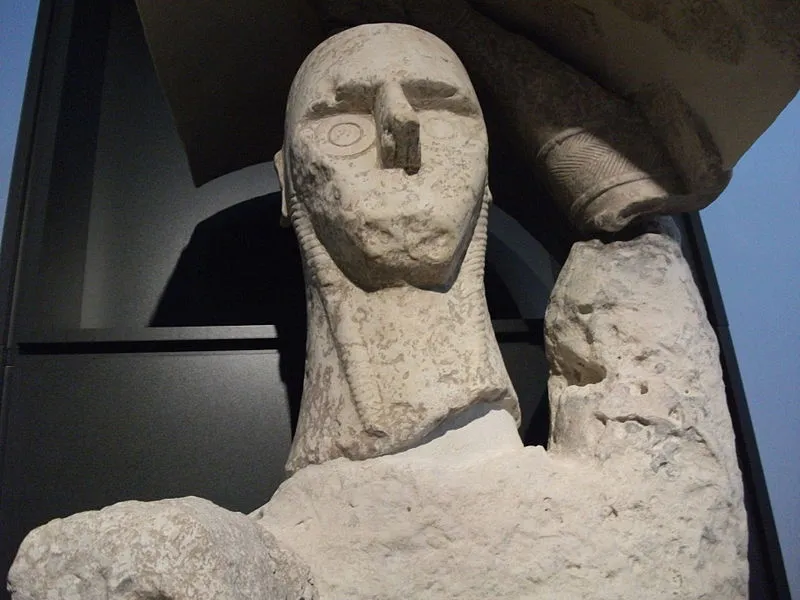 A giant statue of the face and neck of a boxer displayed in a museum.