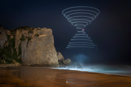 A three-to-four-minute exposure captures the light of a drone as it traces the shape of two cones in the sky along California&#39;s coast.