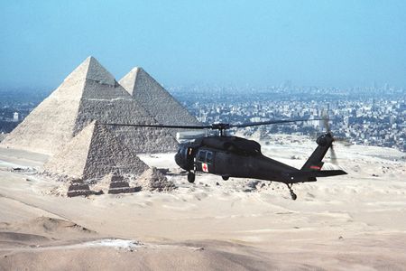 An air-to-air rear view of a UH-60 Black Hawk (Blackhawk) air ambulance helicopter in use during the joint Exercise BRIGHT STAR '83.  Visible in the background are the Great Pyramids and the city of Cairo.