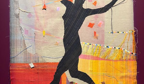 A black silhouette of a jumping woman against a colorful fabric background.