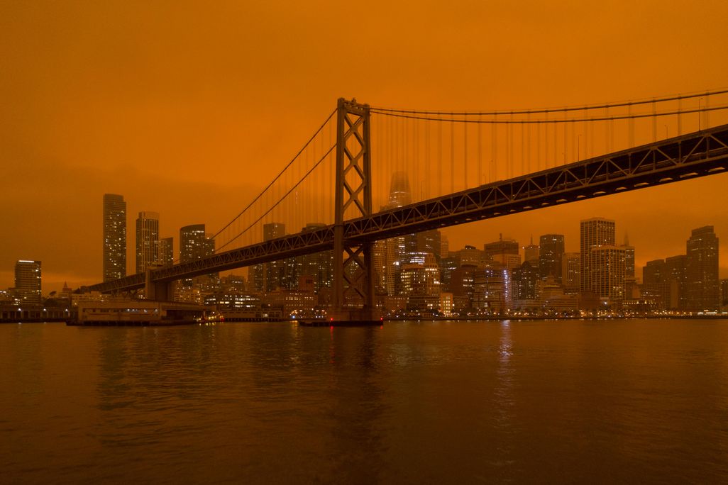 The Golden Gate Bridge and San Francisco skyline with a background of hazy, dark orange sky.