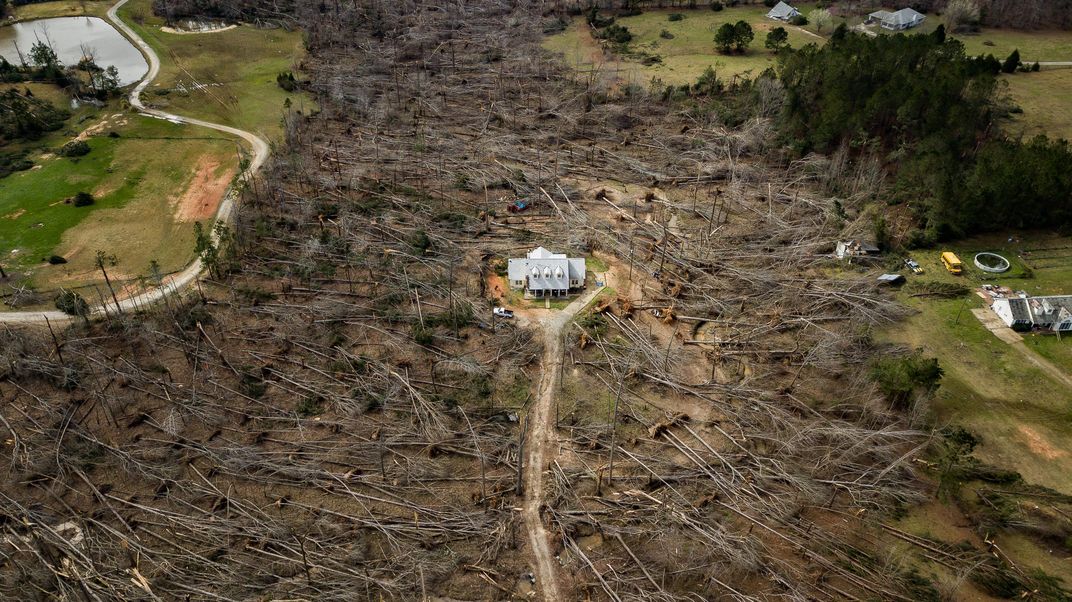 A house stands in the middle of a field decimated by a tornado.