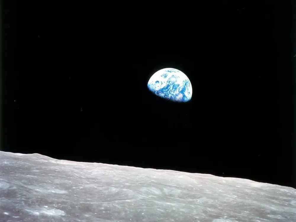 Earth emerges over the moon's horizon.