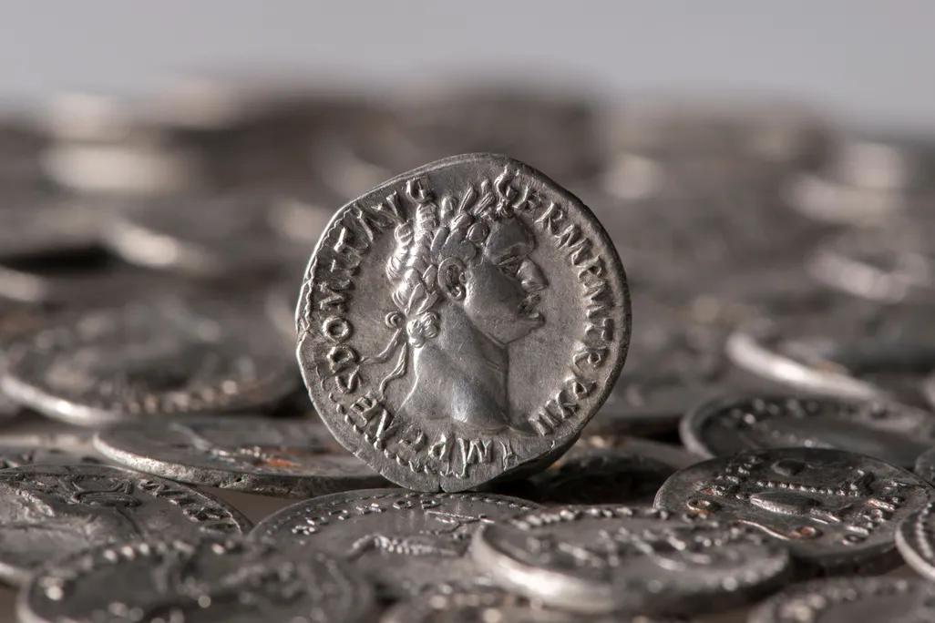 A Roman coin perched on top of other coins