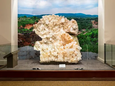 Museum display of the Berns Quartz from the front. The specimen is behind counter-height glass with a backdrop of Arkansas' Ouachita Mountains.