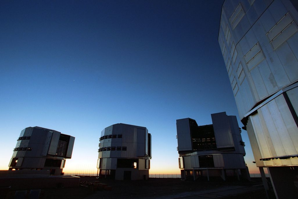 Four large telescopes below an evening sky