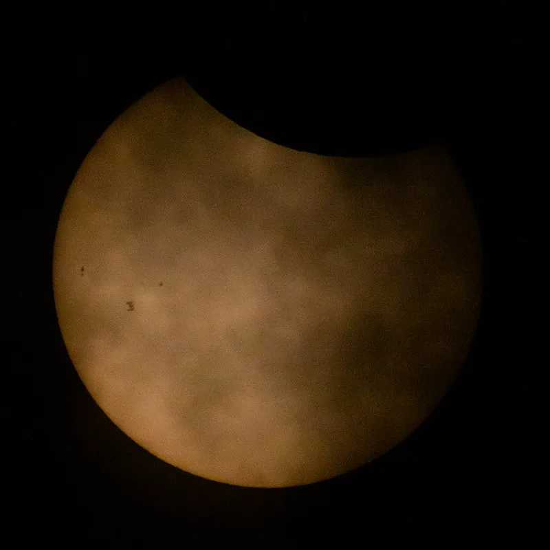 a spacecraft moves across the surface of the partially eclipsed sun, toward the left of the sun's face