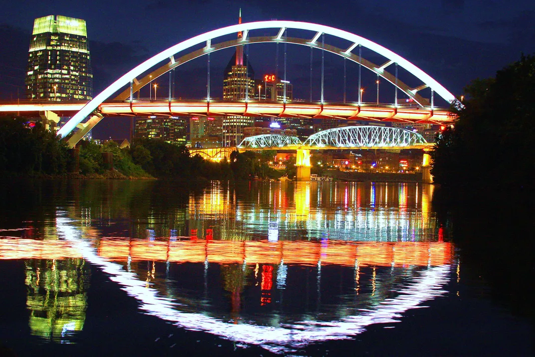 A bridge reflects off the water in Nashville at night