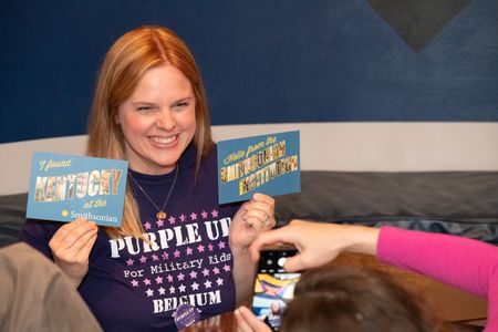 Woman smiling holds up two postcards