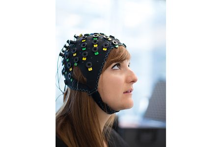 Patients wear a NIRS apparatus—typically a neoprene helmet with dozens of optical sensors sticking out of it.