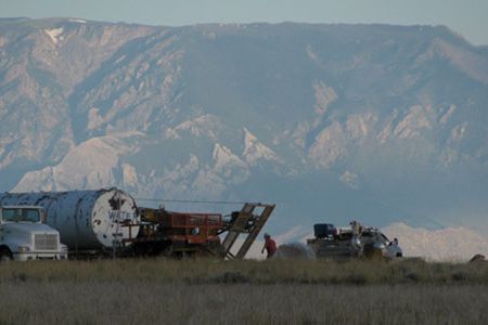 With the Beartooth Mountains looming to the west in the morning light, team members set up the coring rig on Polecat Bench.