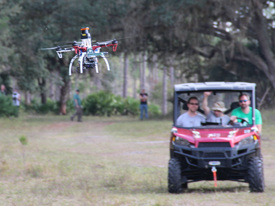 NanoMap researchers follow a drone as it navigates through a forest.