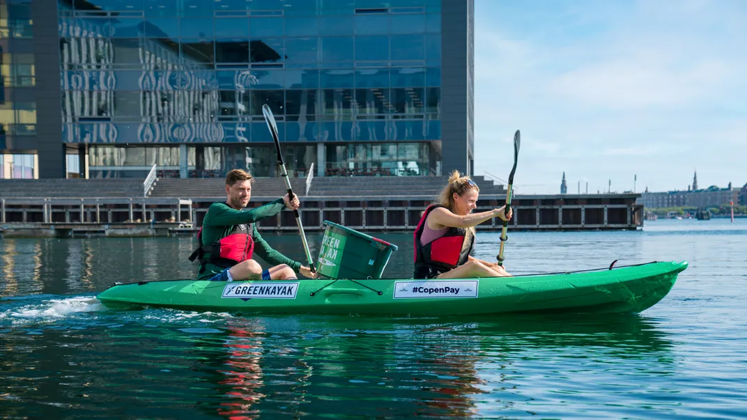A man and a woman in a green kayak paddling on the water