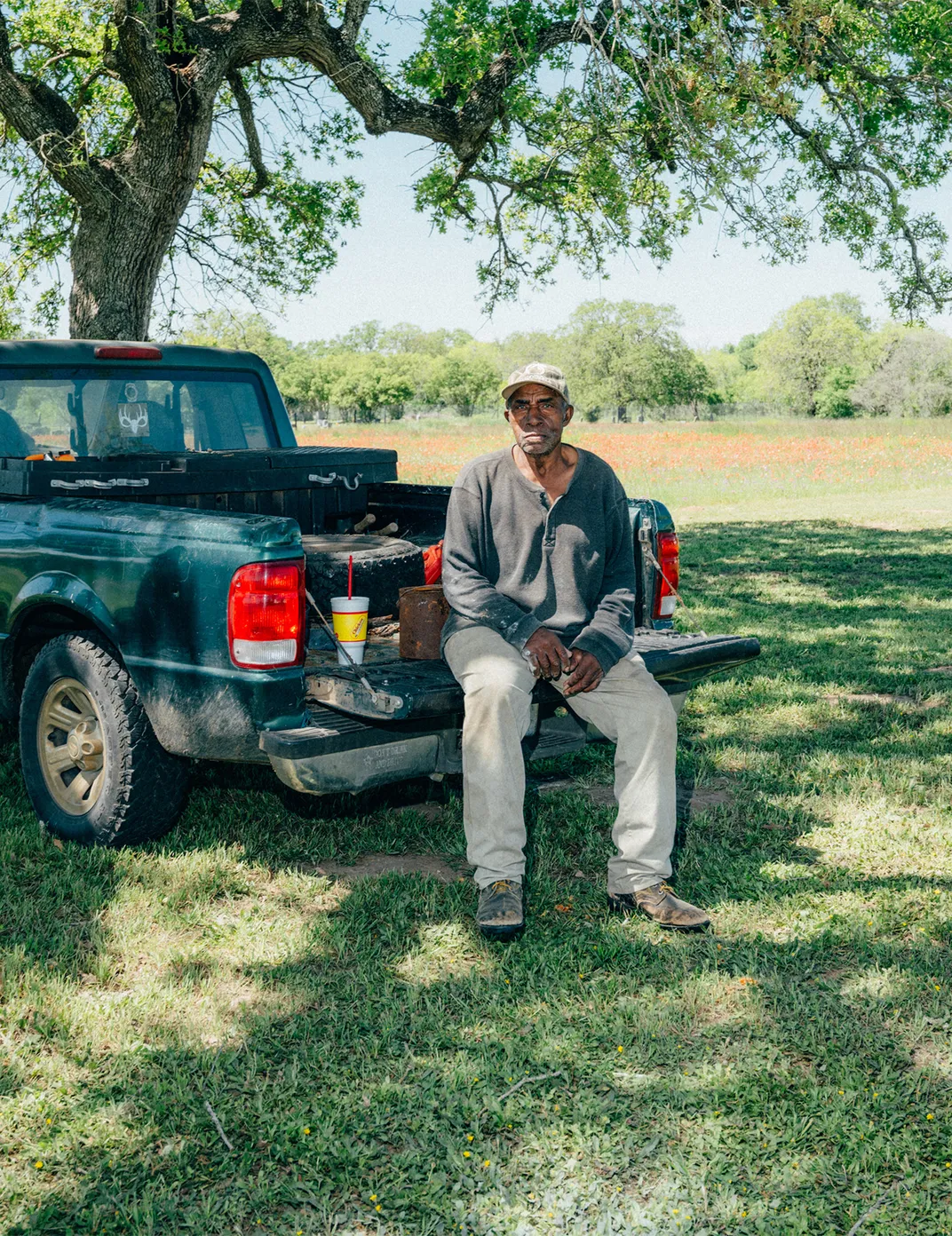 a man sits on the back of a truck bed
