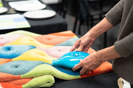 A participant from Cooper Hewitt, Smithsonian Design Museum's "Eva Zeisel: Designing in the Air" workshop explores connections between a Zeisel ceramic prototype and her carpet sample design.