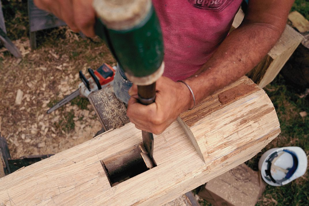 A carpenter works with a chisel
