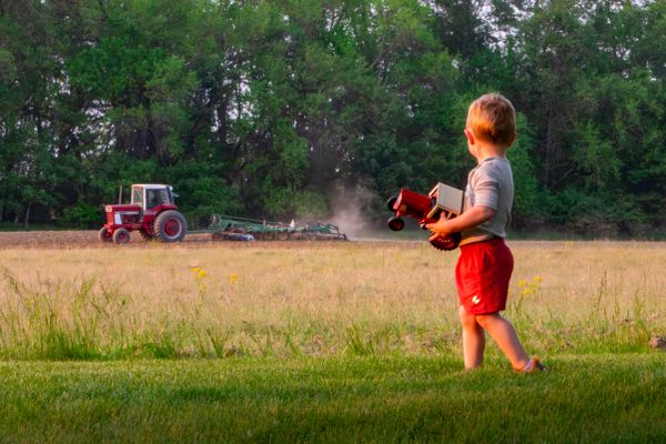 Our son with his tractor while our neighbor plows the field thumbnail
