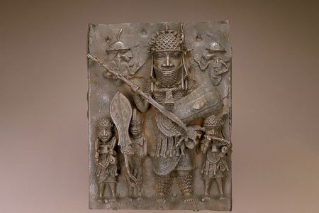 This plaque depicts musicians, a page holding a ceremonial sword and a high-ranking warrior. It numbers among the thousands of works looted by British forces during an 1897 raid of Benin City.