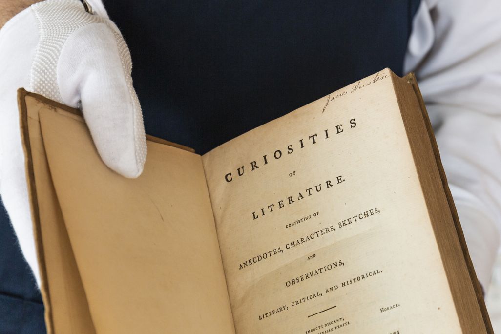White gloved hand holding up an old book