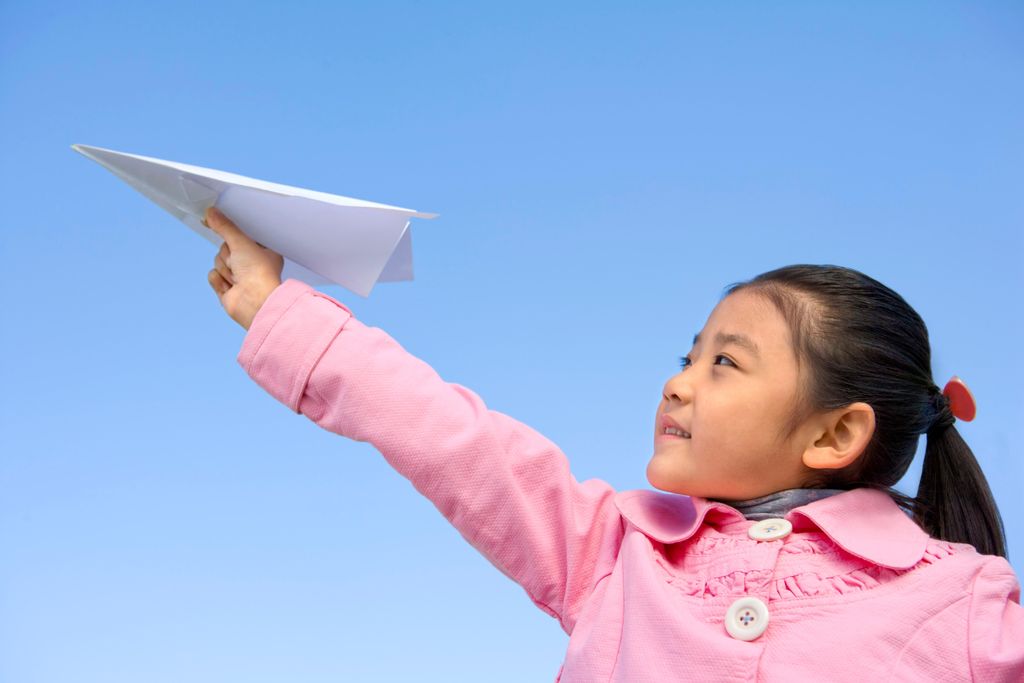 girl throwing paper airplane