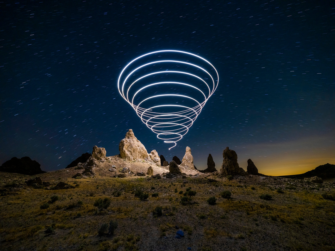 A light cone in the night sky above a rock formation