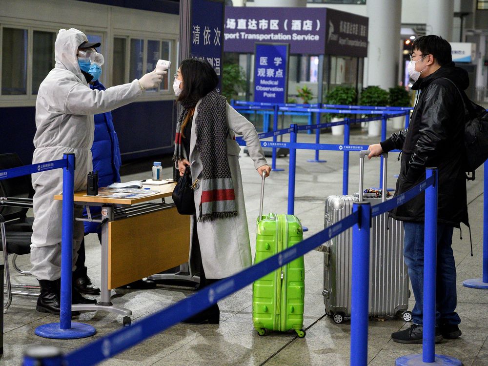 Travelers at Shanghai Pudong International Airport in Shanghai getting their temperatures taken