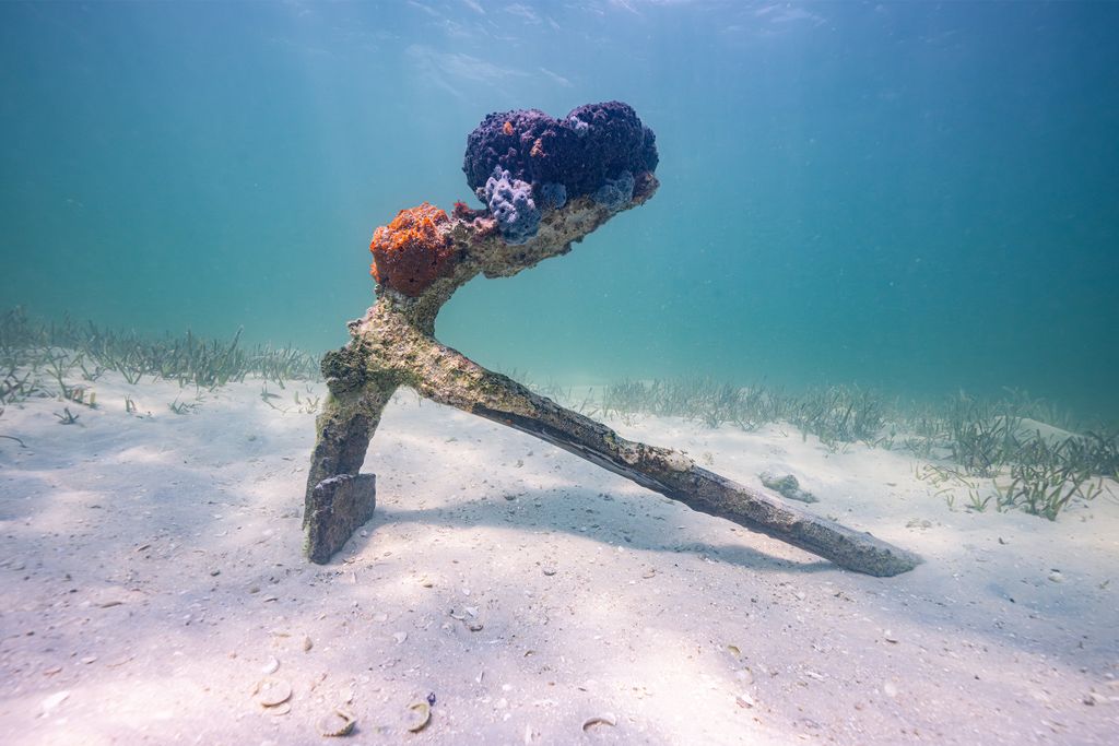Anchor resting on sand under water