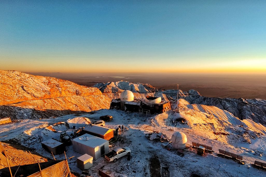 View above current construction of telescope domes on the observatory site, with blue horizon backdrop
