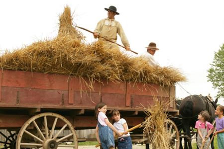 Young guests and living history staffers unload hay.