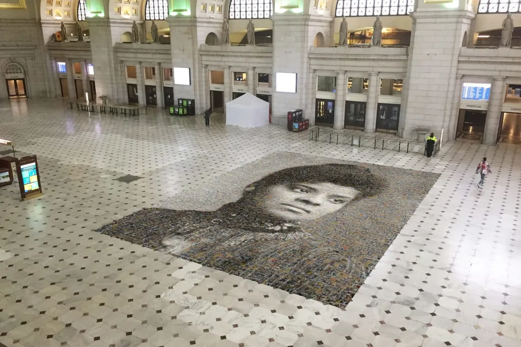 An aerial view of the mosaic, with two people walking nearby for scale; the mosaic takes up 1,000 square feet of floor in Union Station. The station is currently mostly empty due to the Covid-19 pandemic. 