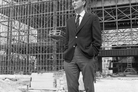 Michael Collins, the Museum's third director, stands before the steel skeleton of the new National Air and Space Museum in July 1974.