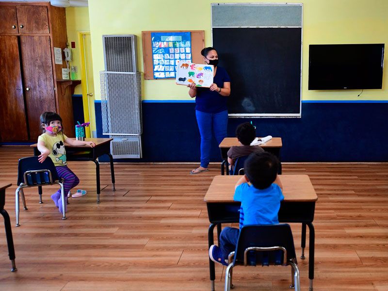 A teacher reads to children in a pre-school class practicing coronavirus precautions