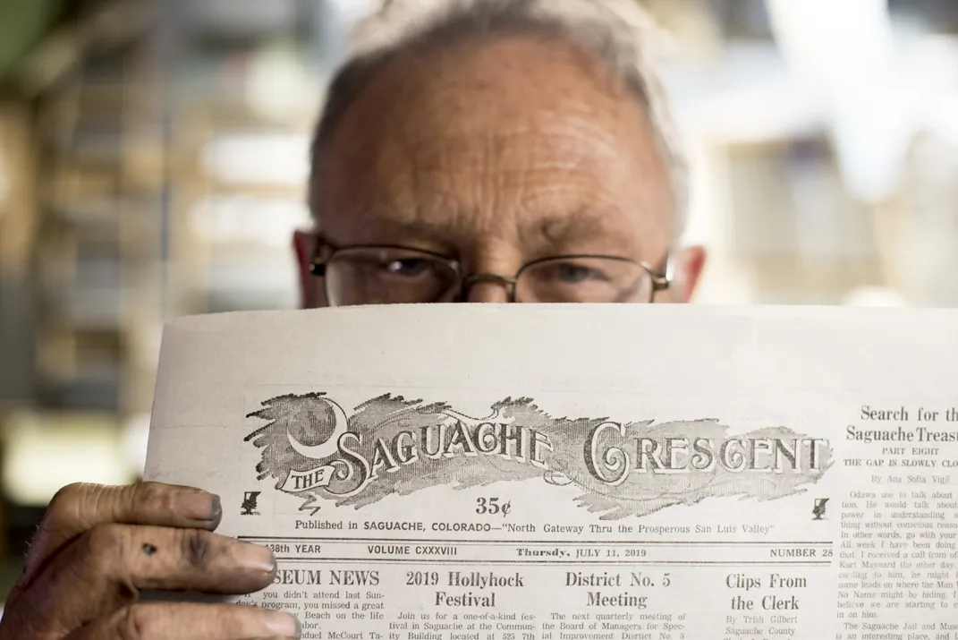 a man examines copy of newspaper print